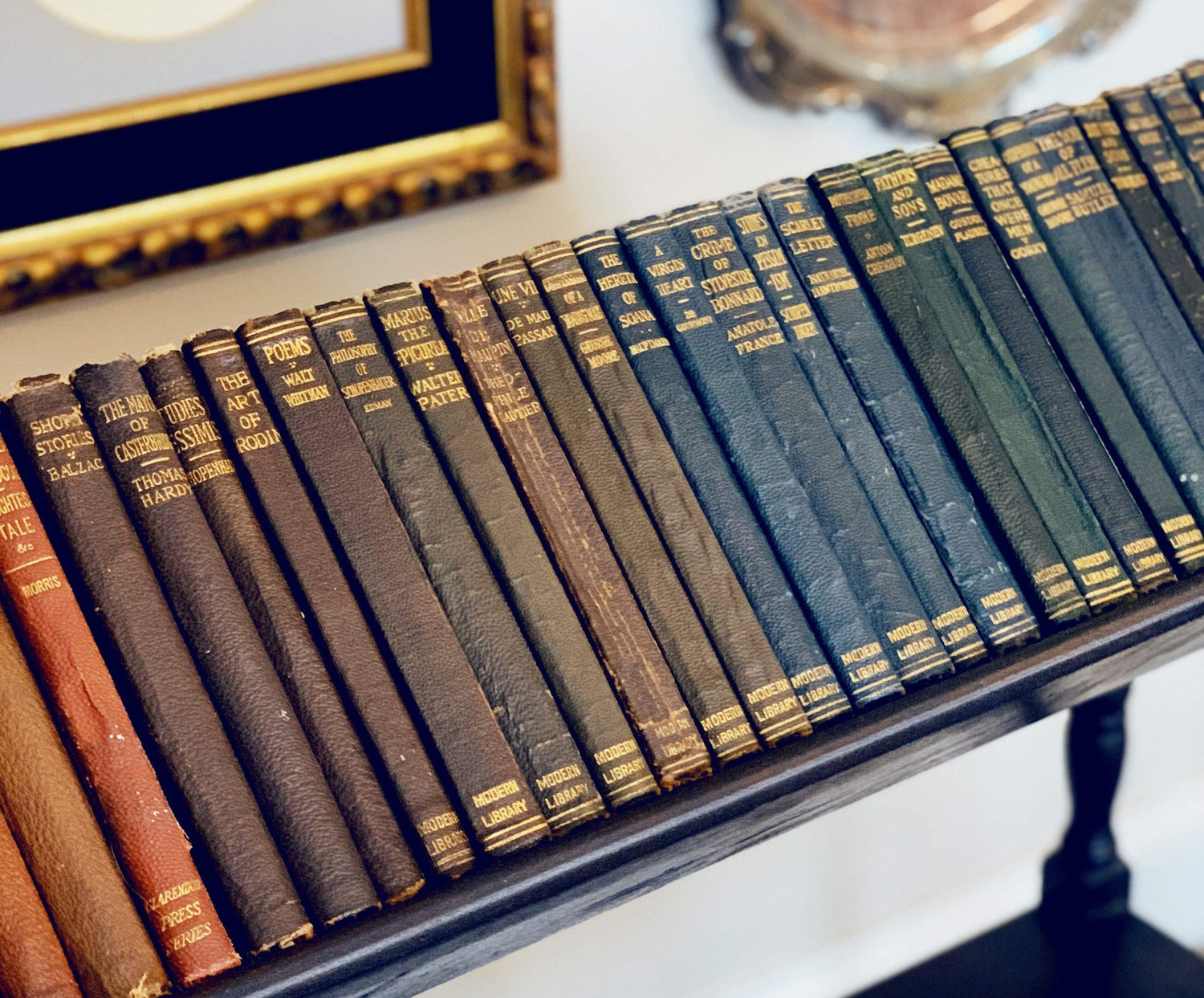 Row of vintage books on a shelf with decorative items in the background